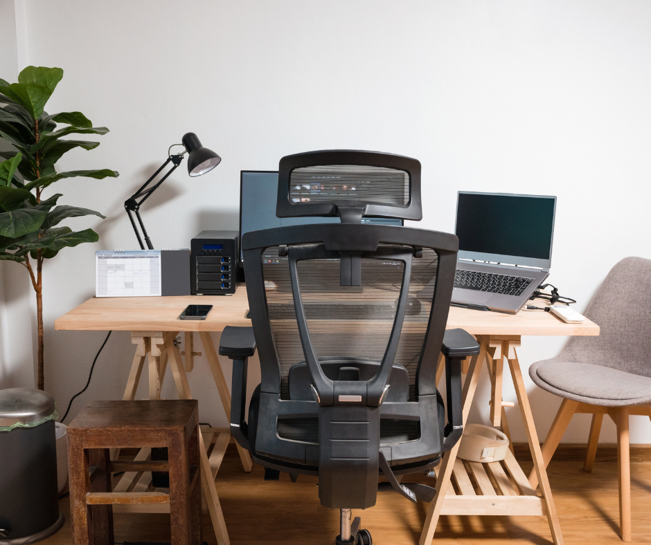 a picture of a workstation with a computer, an office chair, a light, and a plant