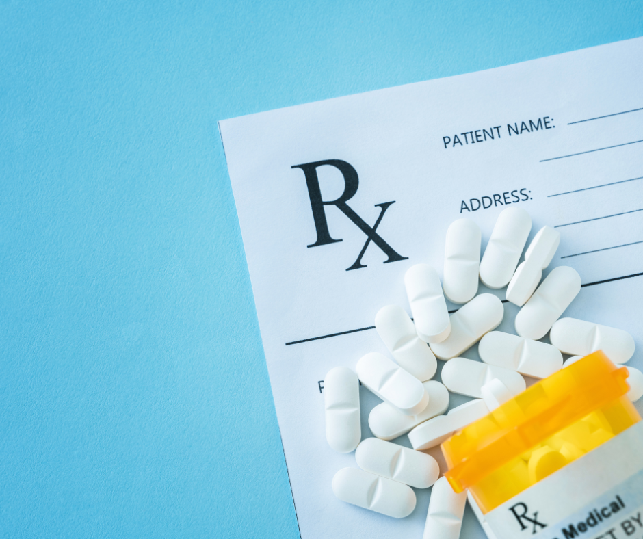 An image of a blank prescription and a yellow bottle of white pills scattered across a blue backdrop
